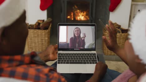 pareja afroamericana con sombreros de santa usando una computadora portátil para una videollamada de navidad con una mujer en la pantalla