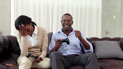 pareja jugando videojuegos en el sofá después del trabajo