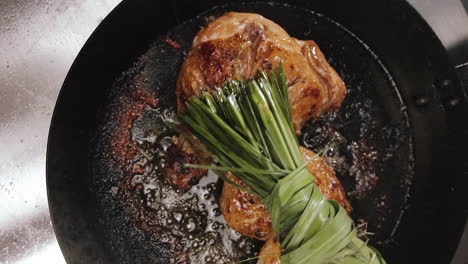 oil dabbing chicken thighs with lemongrass while cooking in a pan