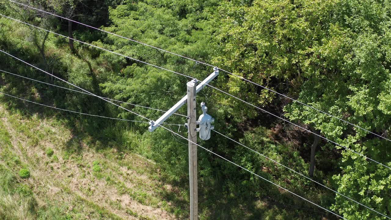 Extreme close-up aerial shot tilting down on a rural utility pole and powerline inspection