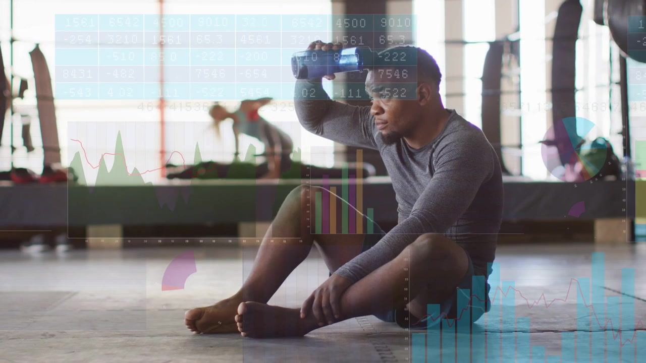 Vertical video: Man on mat resting, reaching blue bottle, cooling, hydrating, charts overlaying gym