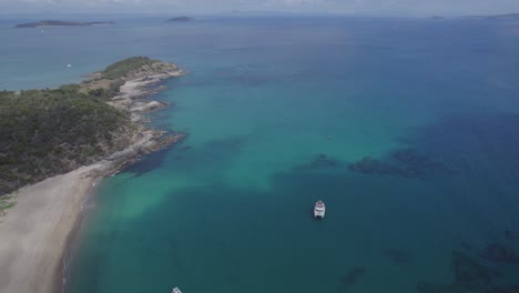 Bahía-De-Pez-Mantequilla-Con-Botes-En-El-Océano-Cerca-De-La-Playa-Secreta-En-La-Isla-Great-Keppel,-Queensland,-Australia---Toma-Aérea-De-Drones