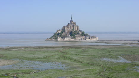 Der-Flug-In-Richtung-Mont-Saint-Michel-Nähert-Sich-Langsam-Und-Verringert-Die-Höhe-Der-Kamera,-Die-Mit-Einer-Schwenkbewegung-Nach-Oben-Endet,-Um-Zu-Zeigen,-Wie-Beeindruckend-Das-Kloster-Ist