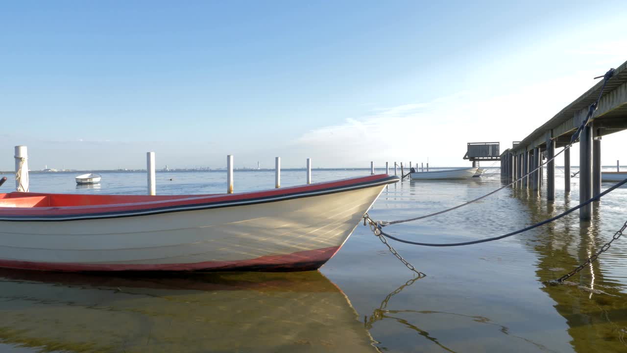 Docked boat rocking by a wooden pier with attached boats