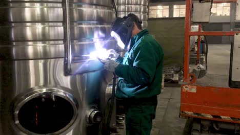 worker welding stainless steel tank, using tig, mig welder, close up, dolly, slide, movement