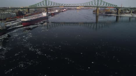 revealing drone shot over water of jacques-cartier bridge in montreal, tilt-up