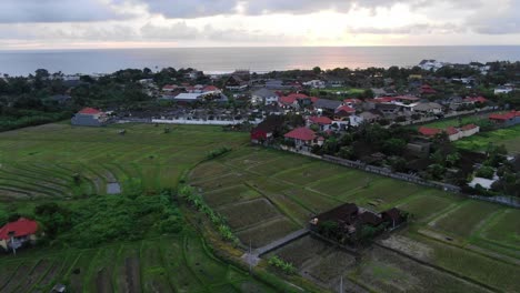 Vista-Aérea-Sobre-Los-Campos-De-Arroz-Bali-Volando-Hacia-El-Océano-Al-Atardecer