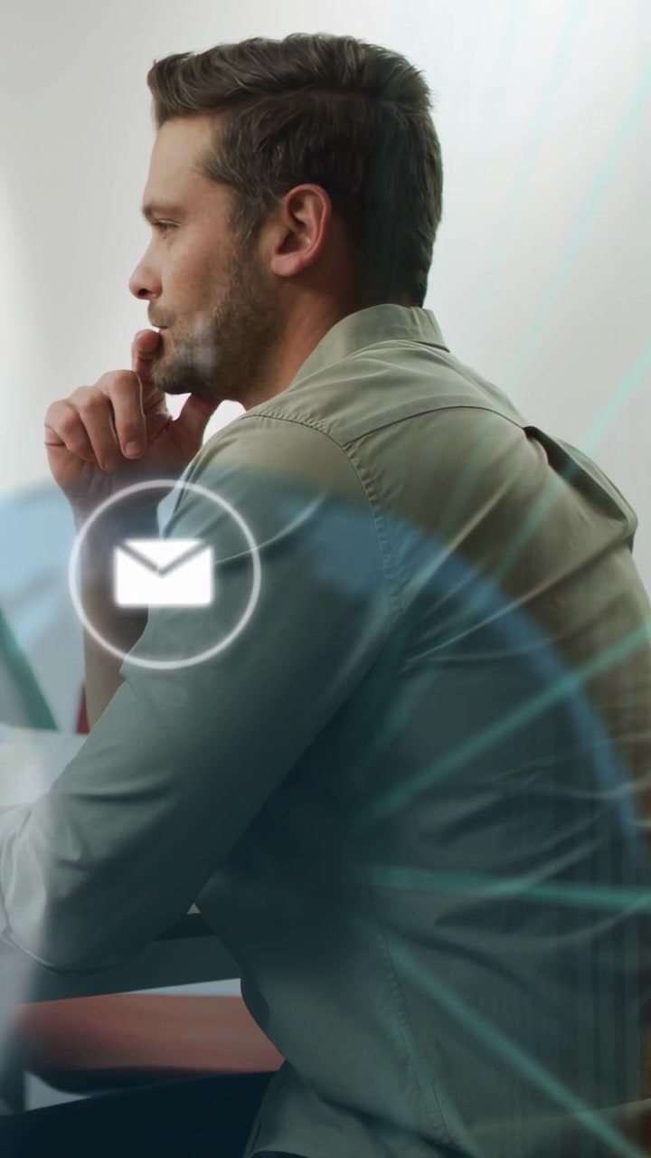 Video verticale: Uomo seduto alla scrivania che pensa mentre sullo schermo appaiono icone di rete e email che segnalano attività aziendali.