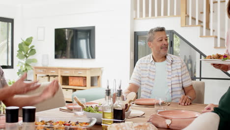 enjoying lunch, senior friends talking and laughing around dining table at home