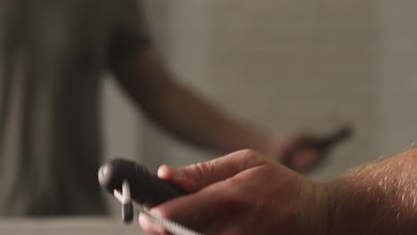 Man's-hands-as-he-jumps-rope-inside-of-gym,-Slide-Right,-Extreme-Close-Up,-Slow-motion