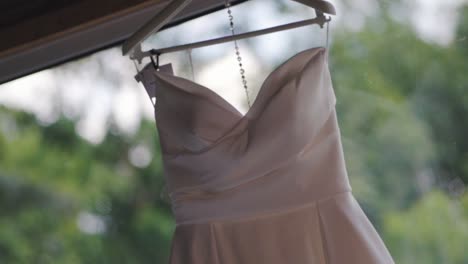 a white wedding dress hanging in an open window in a hotel room