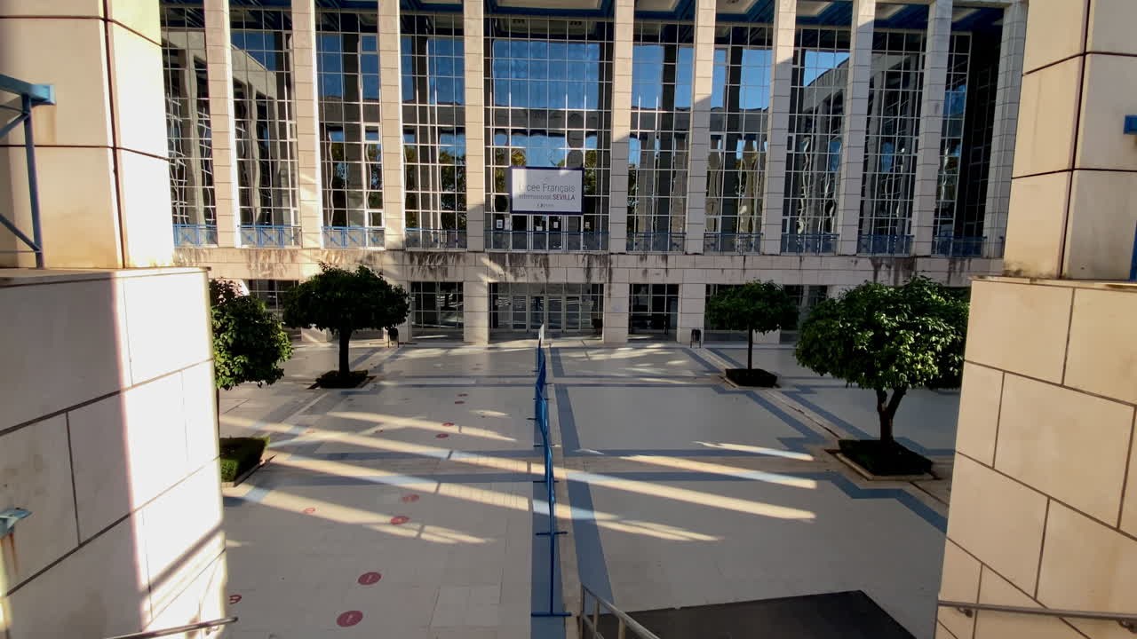 Fachada moderna do Lycée Français em Sevilha sob um céu azul claro, exibindo linhas geométricas e janelas reflexivas