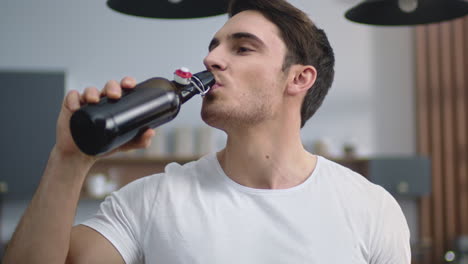 retrato de un hombre alegre abriendo cerveza en la cocina