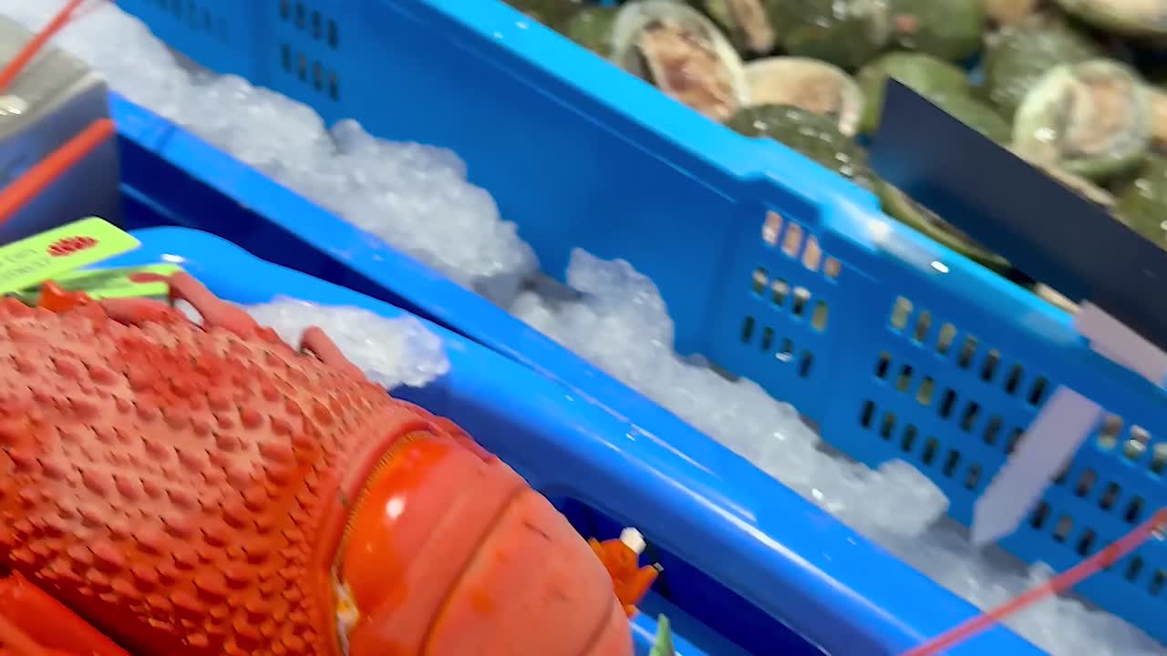 Close-up view of fresh lobsters and crabs arranged on ice in a market setting.