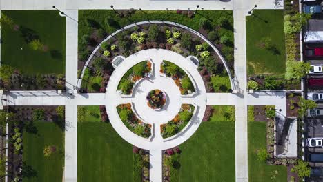 bird's eye drone shot lowering down on a beautifully designed walking path which is surrounded by lush and colorful flowers