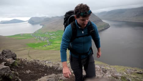 un excursionista sube a un sendero en villingadalsfjall, faroe, con fiordos pintorescos en el fondo