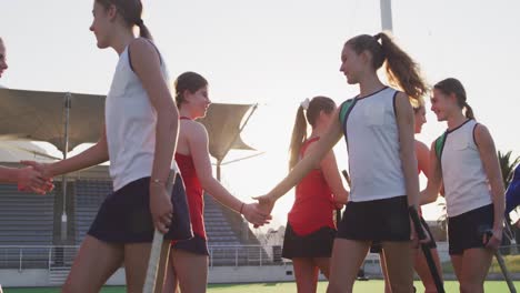 female hockey players shaking hands each other  on the field