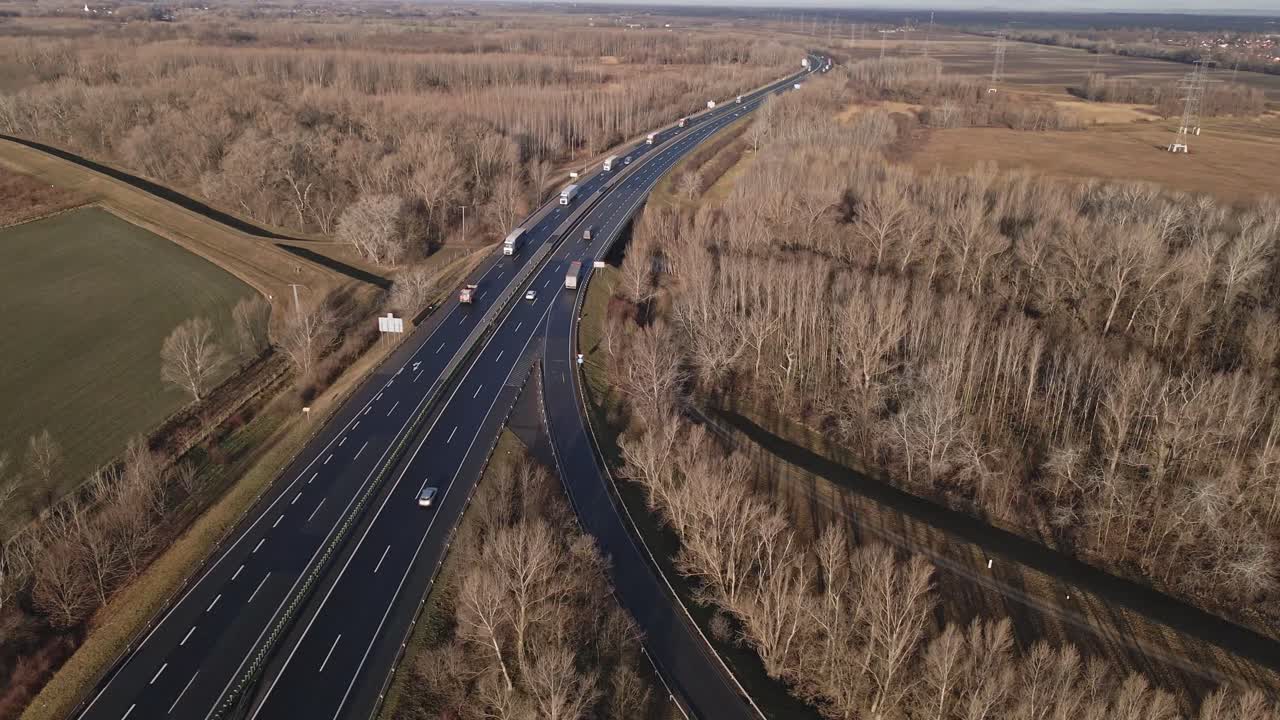 A drone-captured video of a highway stretching through a winter countryside landscape while flies across the highway.