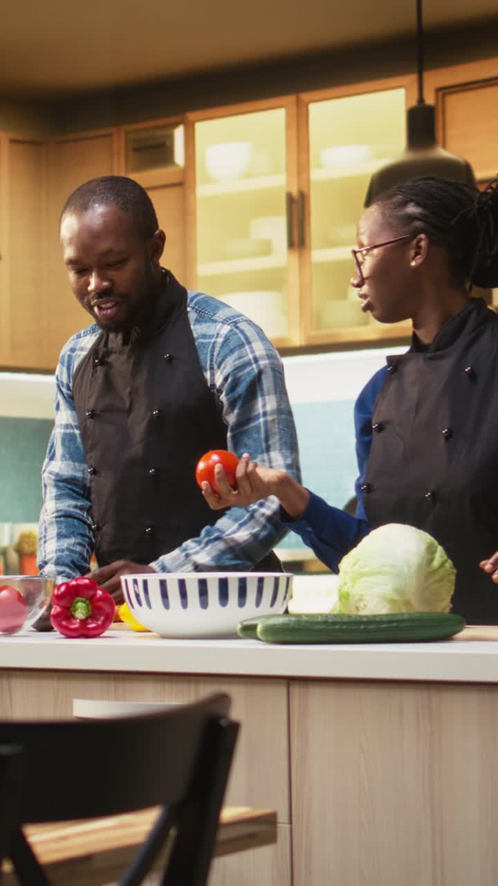 Video verticale. Coppia afroamericana che segue una ricetta online per un'insalata fresca