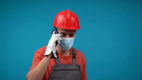 man in hard hat and mask talking on phone