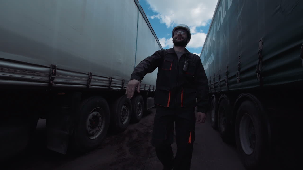 Man in Hard Hat Signaling in a Truck Yard