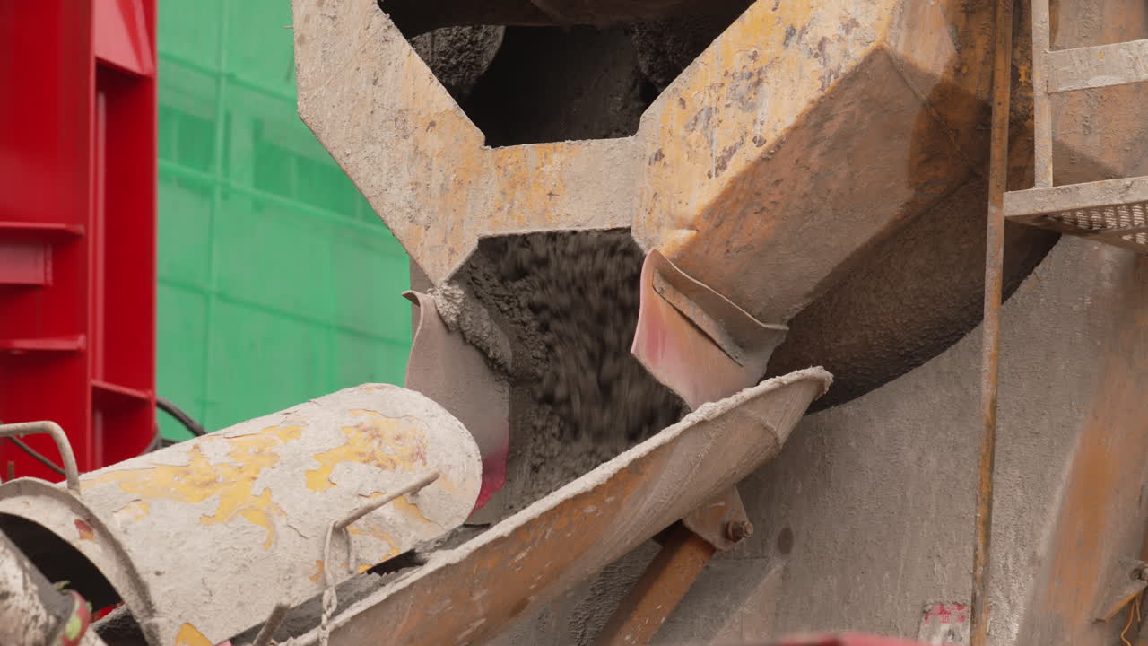 Cemento vertiéndose de la parte trasera de un camión hormigonera en una obra de construcción, primer plano