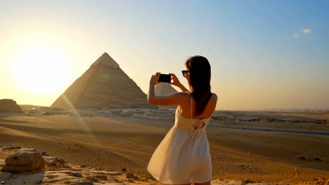 tourist taking photo of giza pyramids at sunset