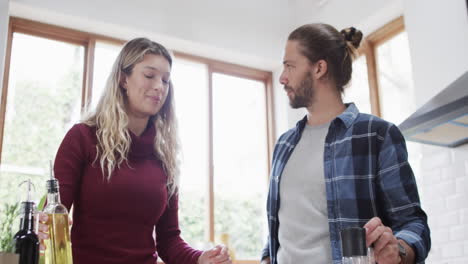 Feliz-Pareja-Diversa-Preparando-La-Cena-En-La-Cocina-De-Casa,-En-Cámara-Lenta