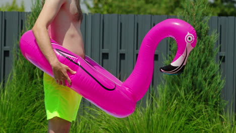 man holding pink flamingo pool float