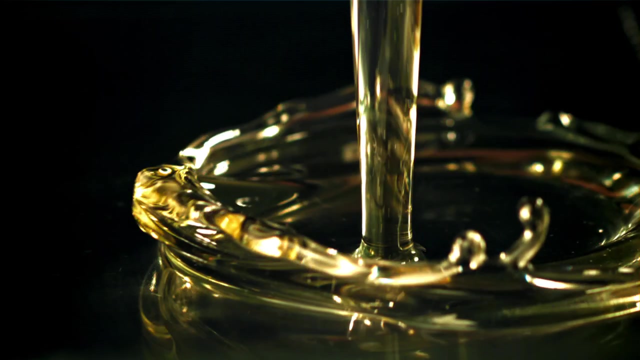 Slow Motion Close-Up of Golden Viscous Liquid Pouring into a Glass
