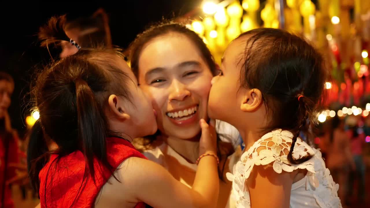 Happy Asian family standing over light from Thai lanna lanterns background at night in Yi Peng Festival.