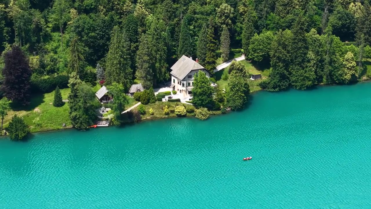 Ripresa con drone di una villa sul lago sulle acque turchesi del Lago di Bled, Slovenia, in una soleggiata giornata estiva.