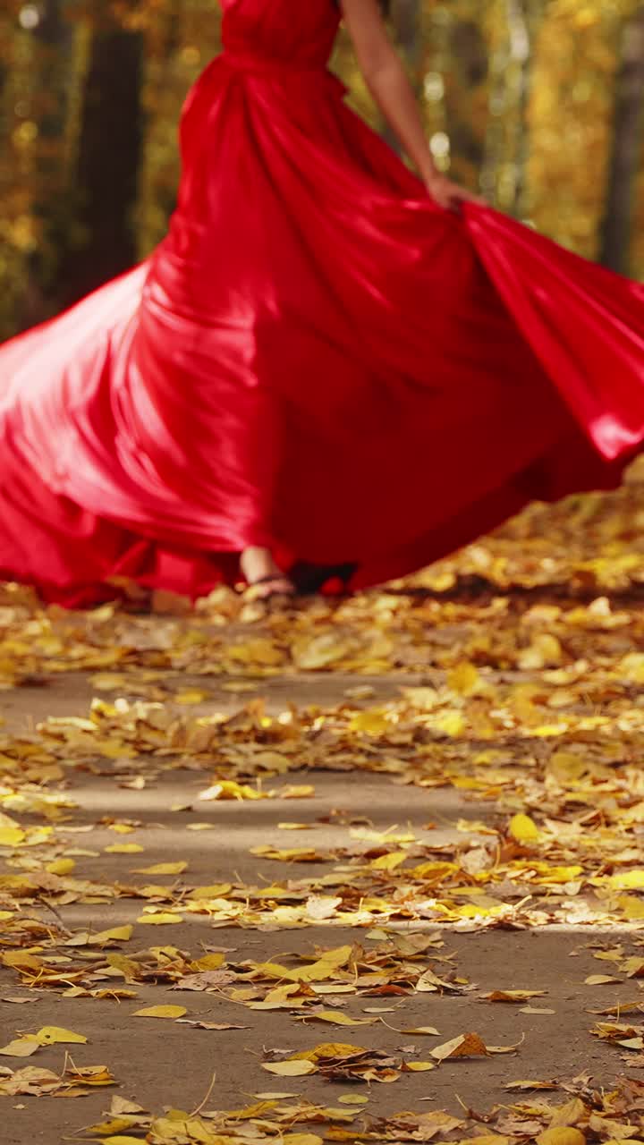 A Stunning Display of Autumn Elegance: A Figure in a Flowing Red Dress Amidst a Vibrant Landscape of Fallen Leaves