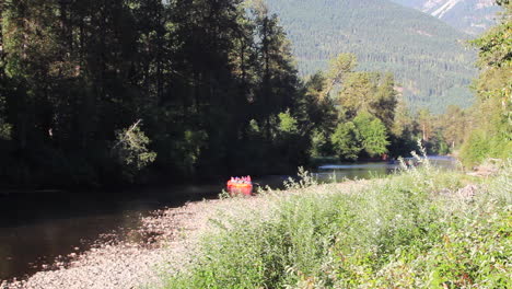 Rafters-in-orange-boat-float-down-picturesque-morning-mountain-river