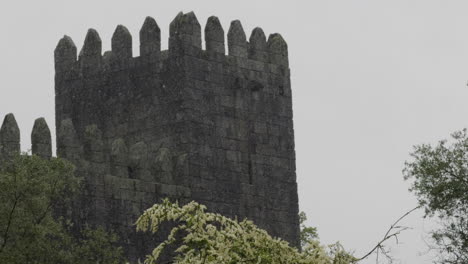 fortress stone tower on a rainy day surrounded by trees at guimaraes castle