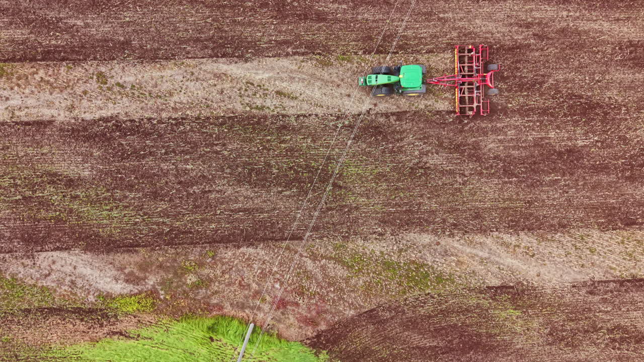 Un trattore lavora in un campo preparando il terreno per la semina in una zona rurale durante il giorno.