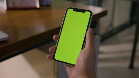 Statische-Zwischenaufnahme-Eines-Mannes-Mit-Smartphone-Und-Chroma-Greenscreen-In-Einer-Unternehmensumgebung