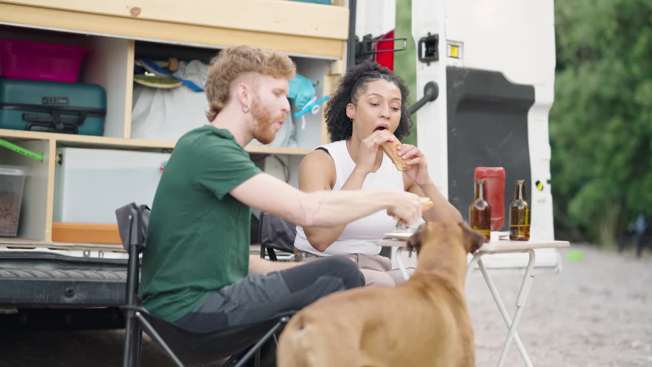 Couple Enjoying a Meal with Their Dog While Camping in Their Van