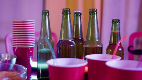 closeup of beer bottles and plastic cups on a party table at home