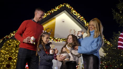 family celebrating christmas in front of decorated house