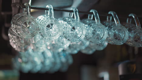 clean glass mugs for beer hang on metal rack in empty pub