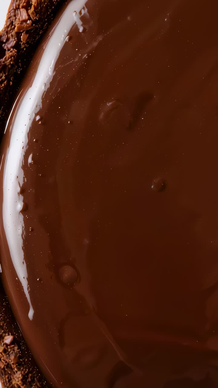 Vertical video: Shifting chocolate settling and smoothing in kitchen bowl, crumbs clinging rim