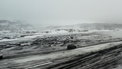 Two-4x4-trucks-driving-on-unpaved-off-road-trail-in-winter-muddy-landscape