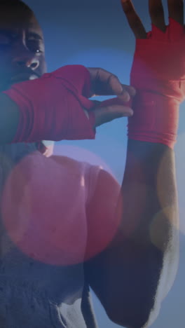 colorful spots of light against african american male boxer applying bondage tape on hands