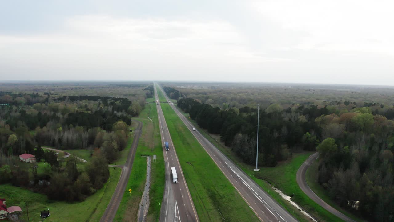 Semi trucks driving on American style highway in high angle drone view