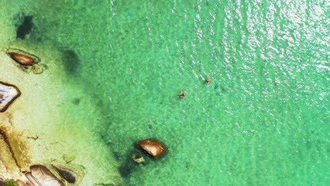 Vibrant-clear-water-of-shallow-turquoise-lagoon-caving-old-limestone-cliffs-on-beautiful-shore-of-tropical-island-in-Thailand