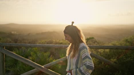 Una-Mujer-Sonriente-Y-Feliz-Mira-La-Cámara-Bajo-El-Reflejo-Del-Sol-Al-Aire-Libre