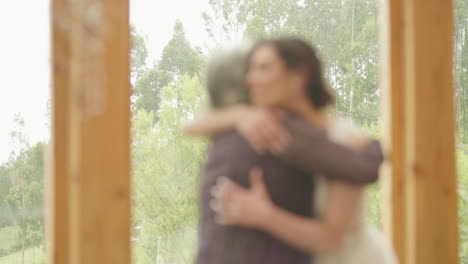 a touching clip shows a mother and her daughter, the girlfriend, giving each other a strong, loving hug near a large window with a beautiful natural landscape in the background.