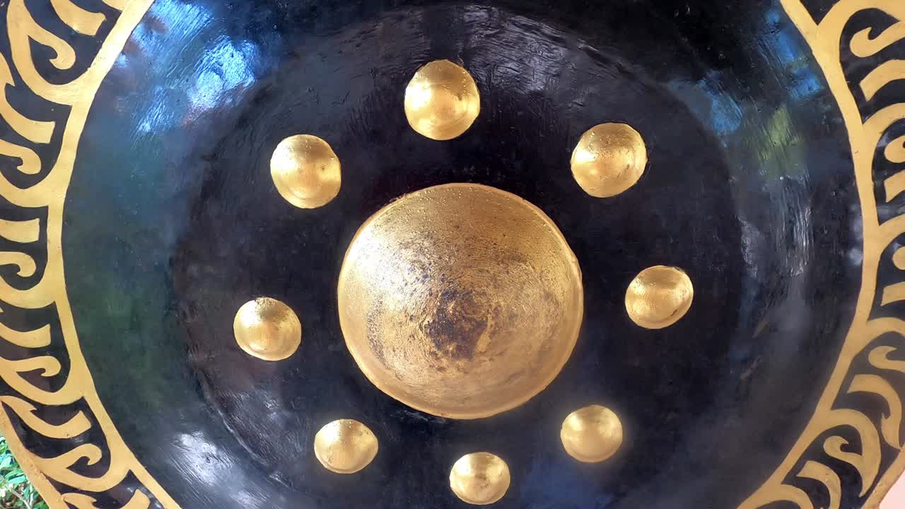 Black sacral gong with a golden pattern is swaying after hitting