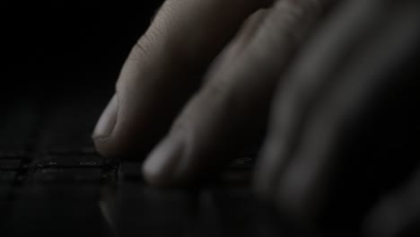 close-up of hands typing on a laptop keyboard at night